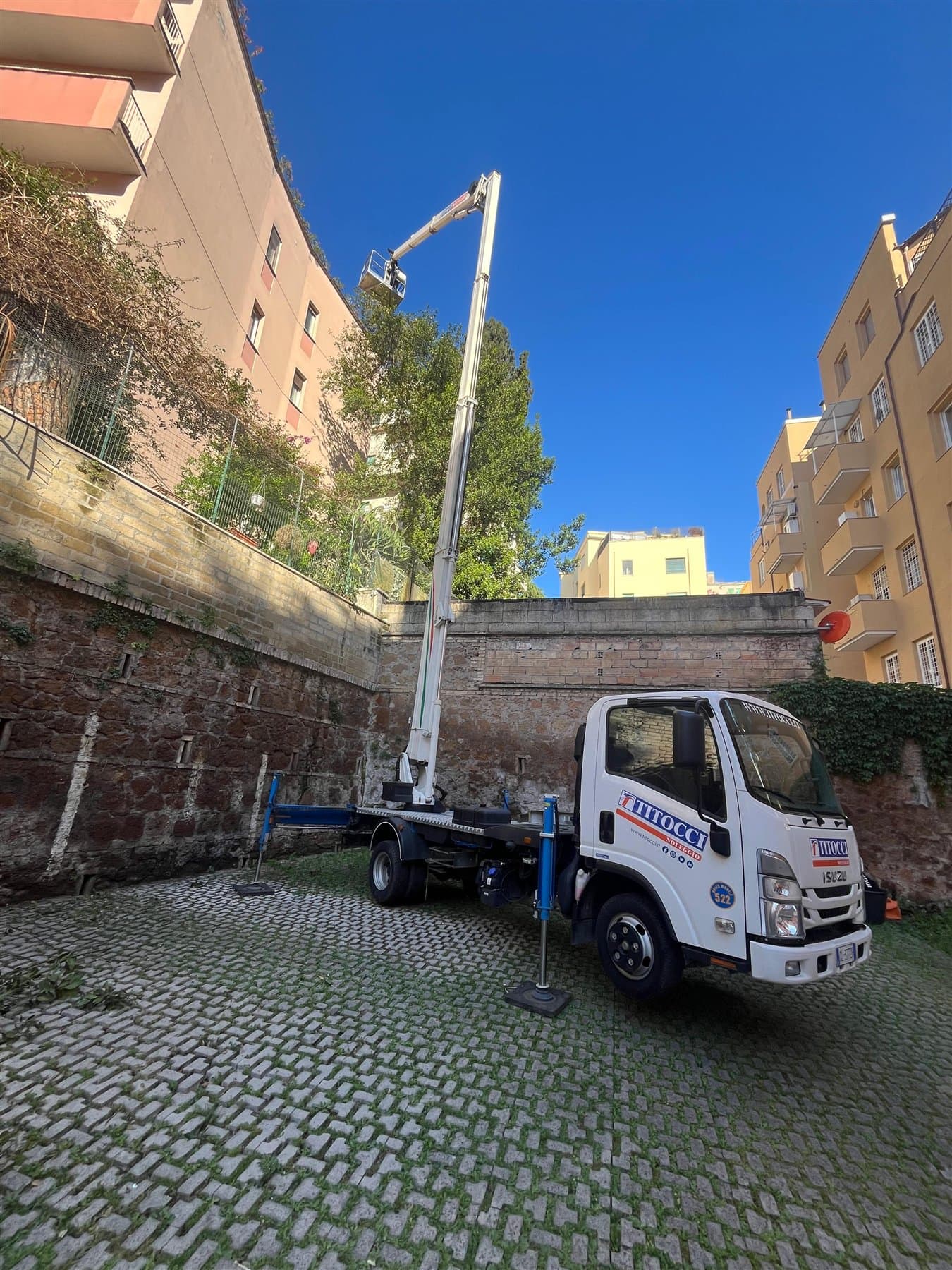 Piattaforma di lavoro elevabile posizionata in un cortile urbano
